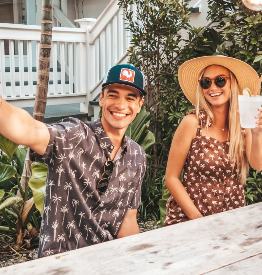 a couple sitting at a wooden table outdoors enjoying a refreshment