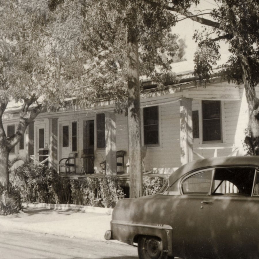 A historic photo of the Merlin Hotel with an antique car parked out front.