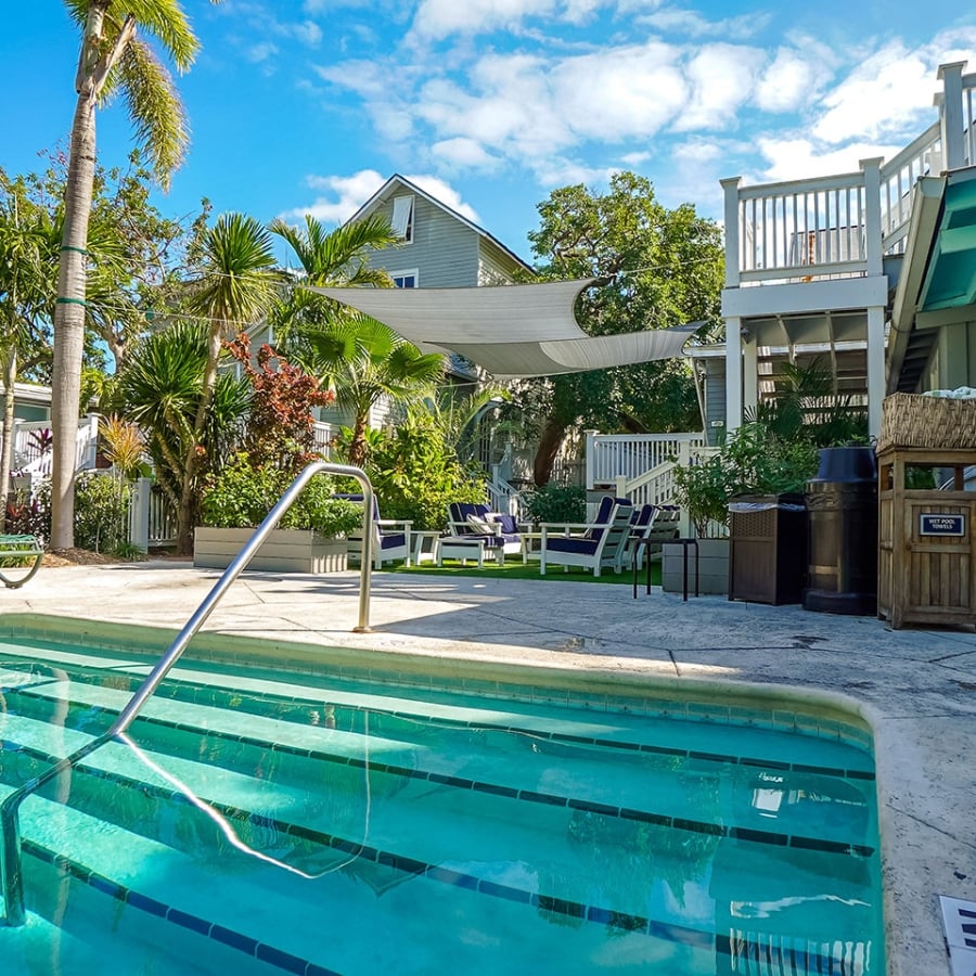 A beautiful outdoor pool surrounded by green deck chairs and palm trees