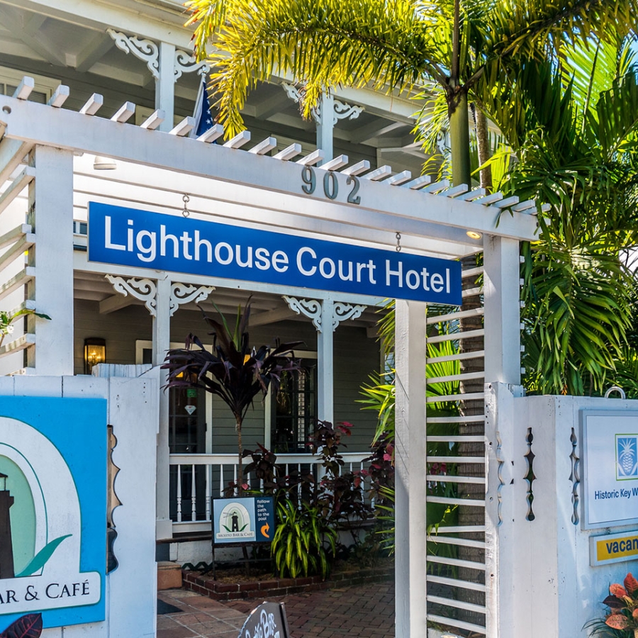 The outside of the old Lighthouse Court Hotel with a white wooden fence and flower planters