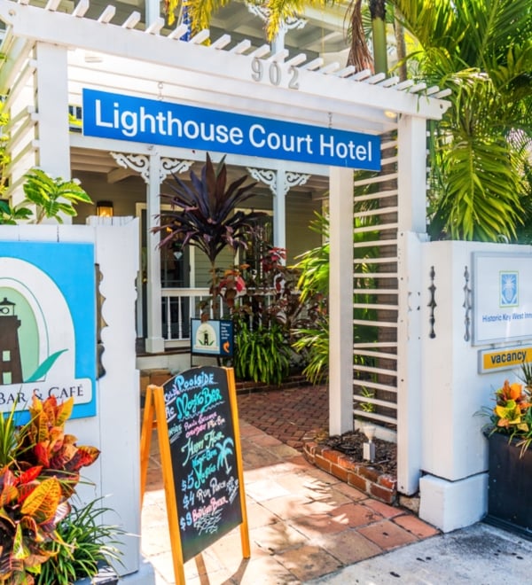 The outside of the old Lighthouse Court Hotel with a white wooden fence and flower planters