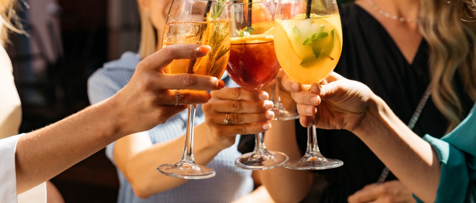 Friends toasting, saying cheers holding summer cocktails.