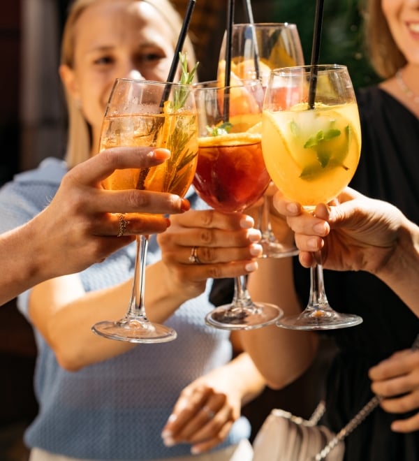 Friends toasting, saying cheers holding summer cocktails.