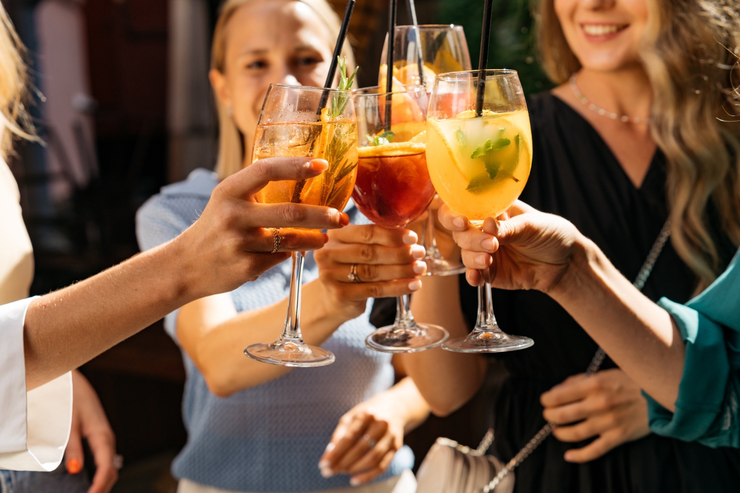 Friends toasting, saying cheers holding summer cocktails.